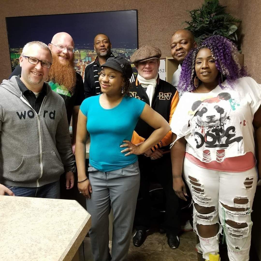 A group of people posing for a picture with one wearing a word hoodie