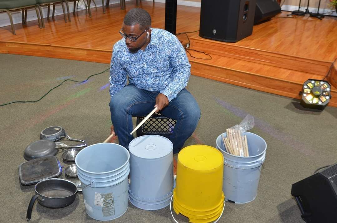 A man is kneeling on the floor playing drums.