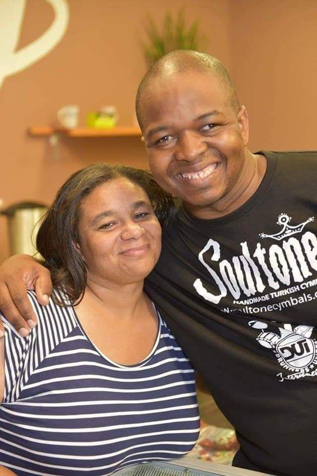 A man and a woman are posing for a picture . the man is wearing a soultone shirt.