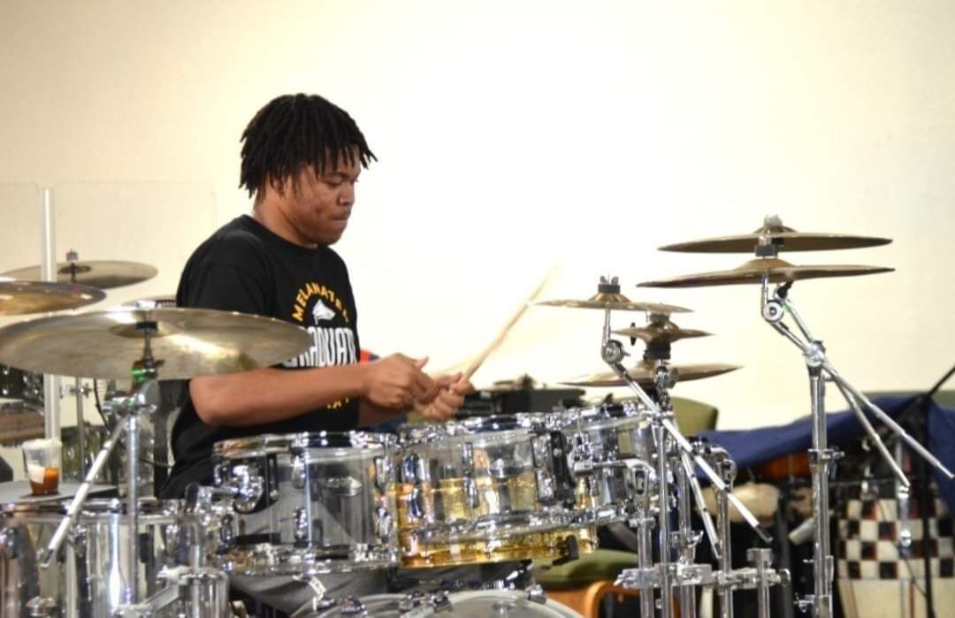 A man in a black shirt is playing drums