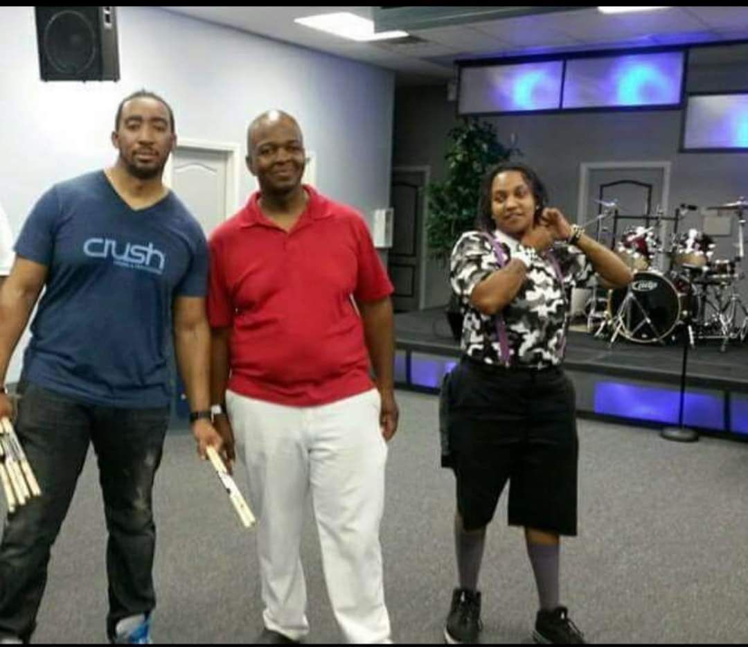 A man wearing a crush shirt stands next to two other men