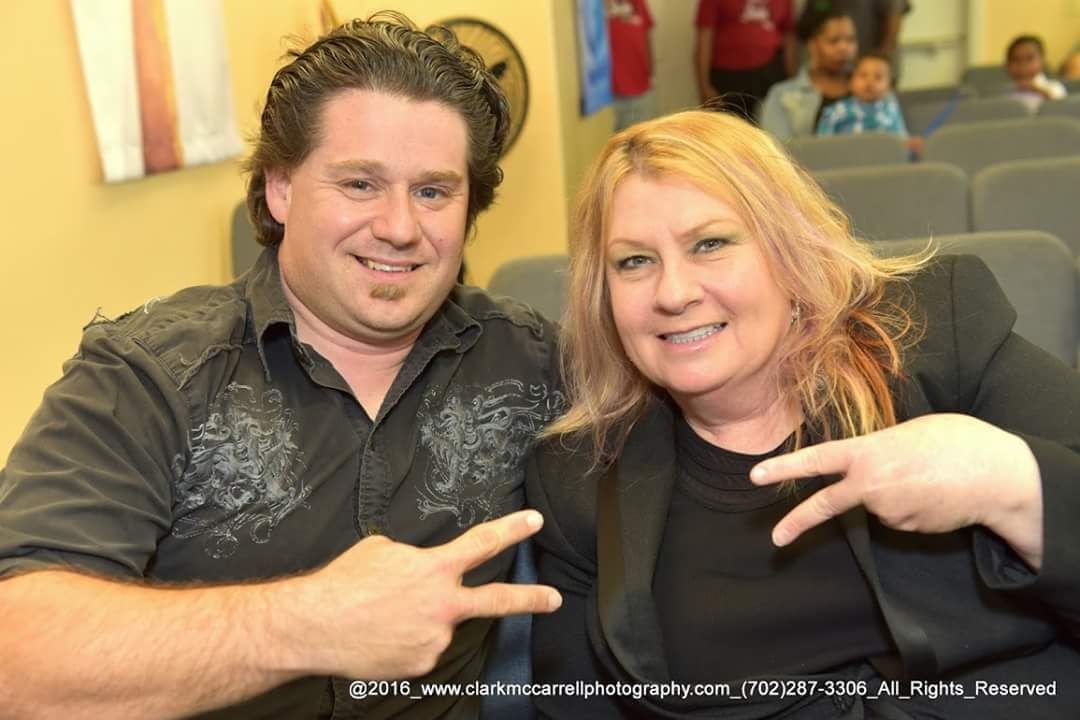 A man and a woman are posing for a picture and pointing at the camera.