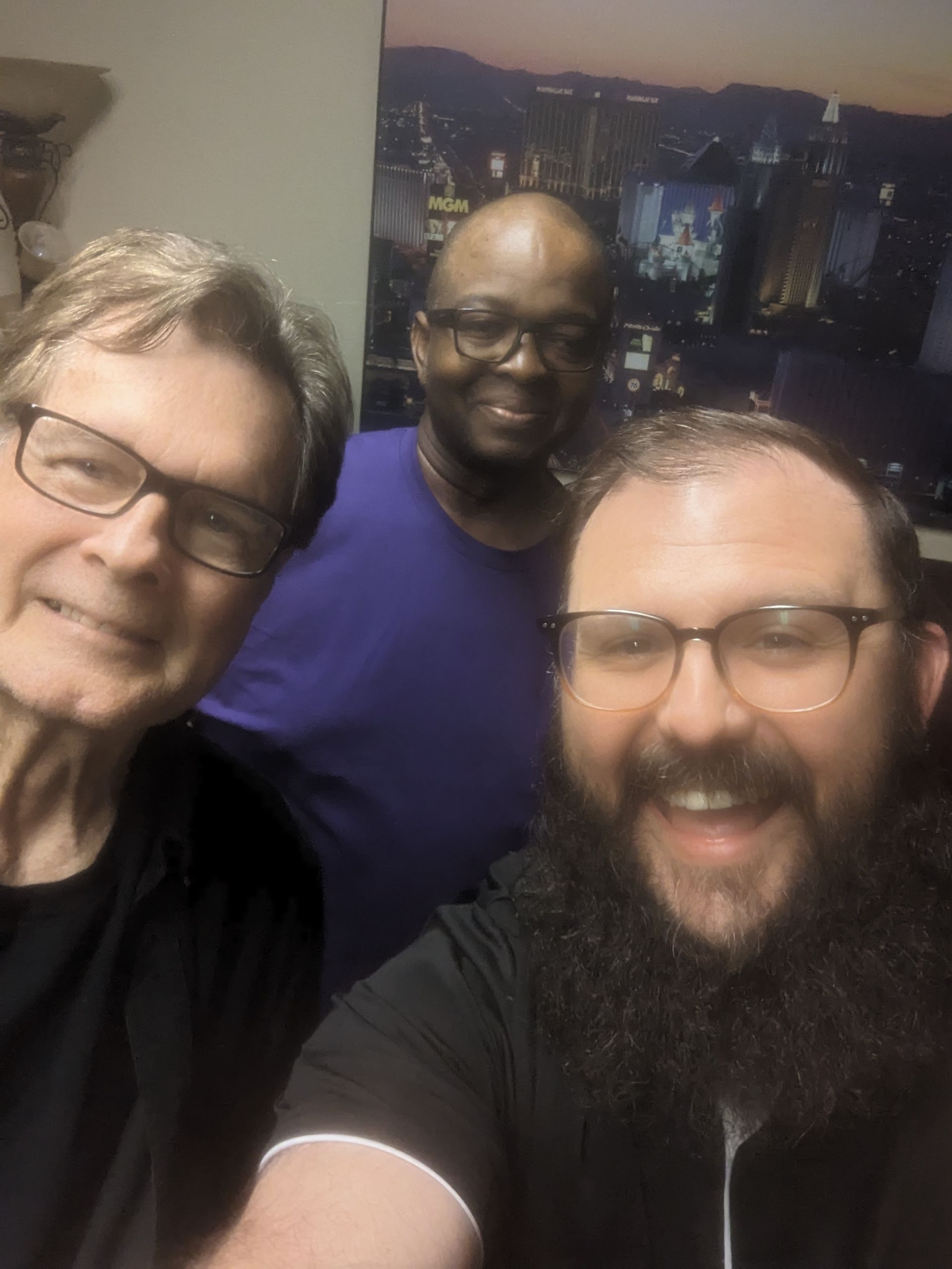 Three men are posing for a picture together and one of them has a beard.