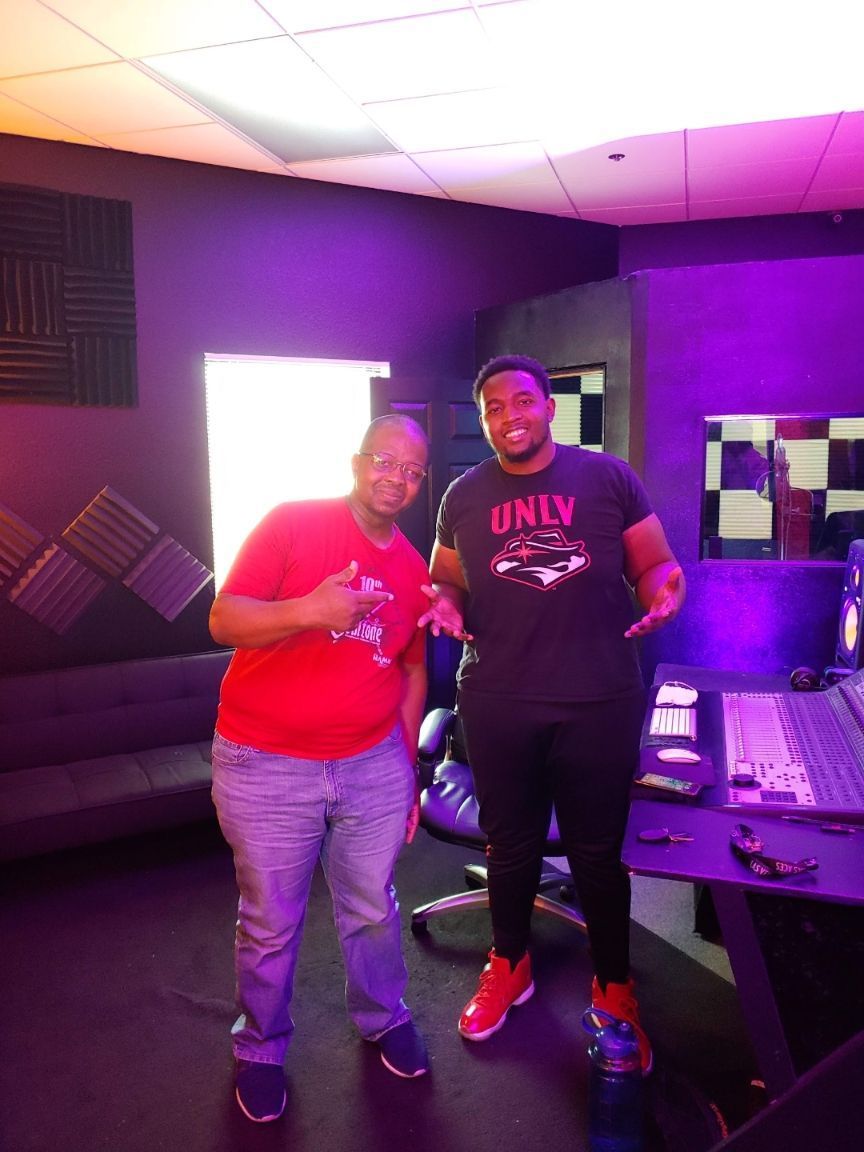 Two men are posing for a picture in a room with purple lights