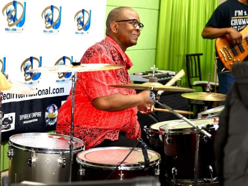 A man in a red shirt is playing drums