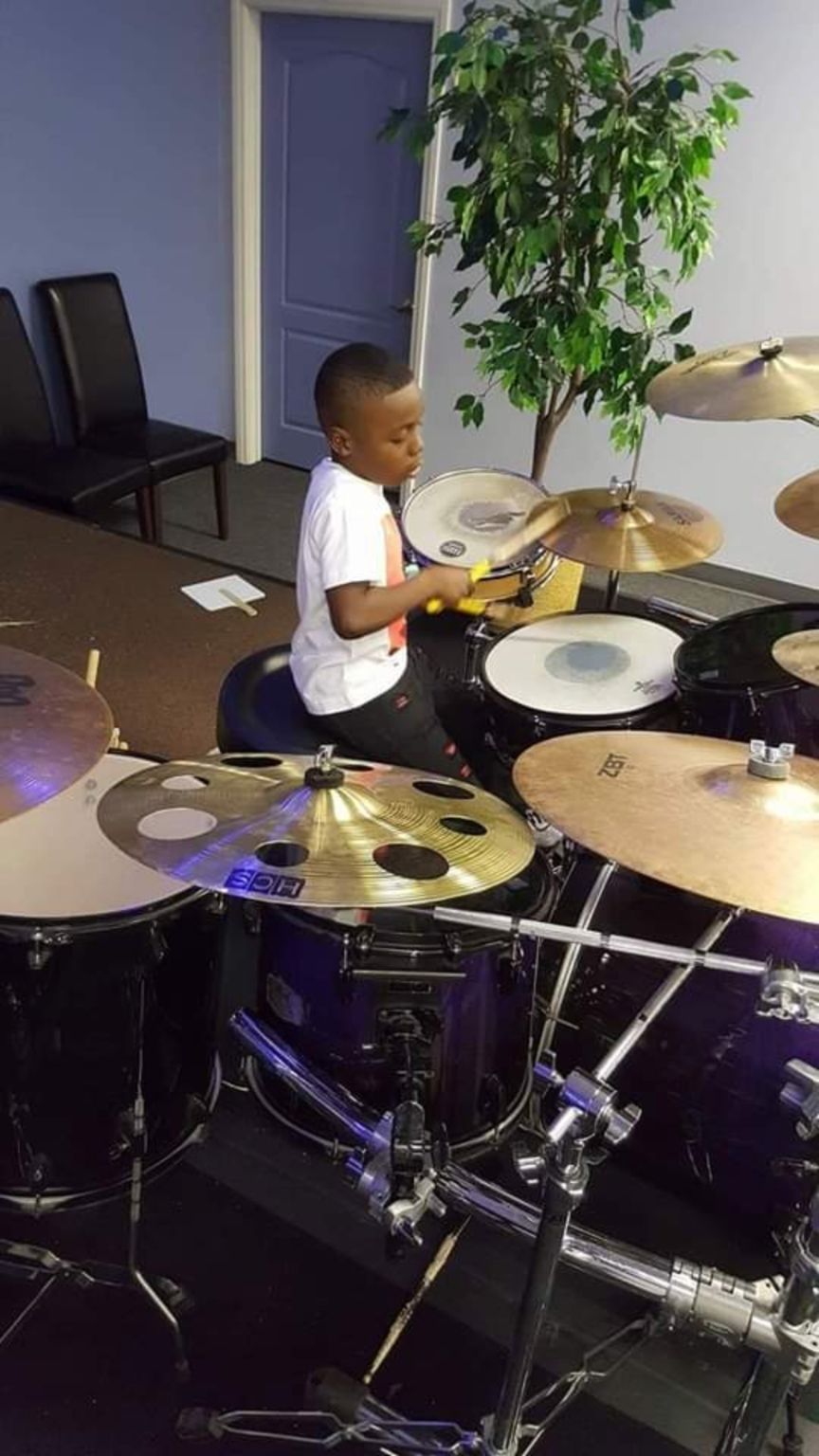 A young boy is playing drums in a room.