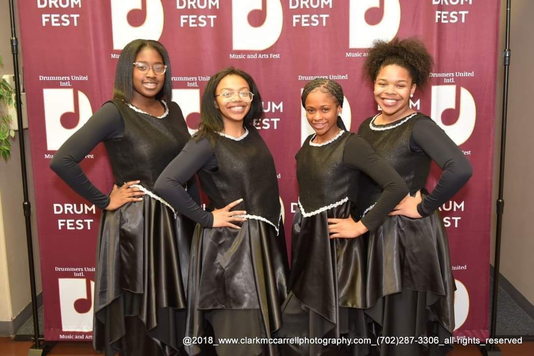 A group of girls standing in front of a drum fest banner
