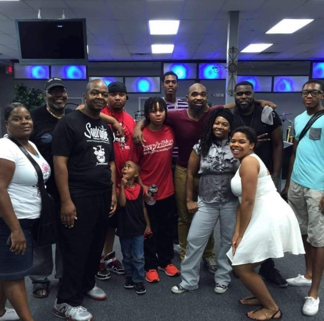 A group of people posing for a picture with one man wearing a shirt that says supreme