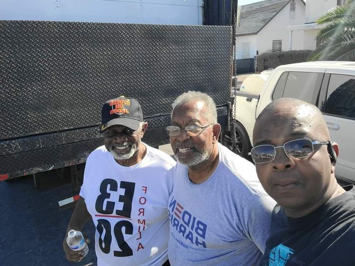 Three men are posing for a picture in front of a truck.
