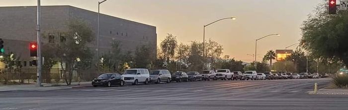 A row of cars are parked on the side of the road at an intersection.