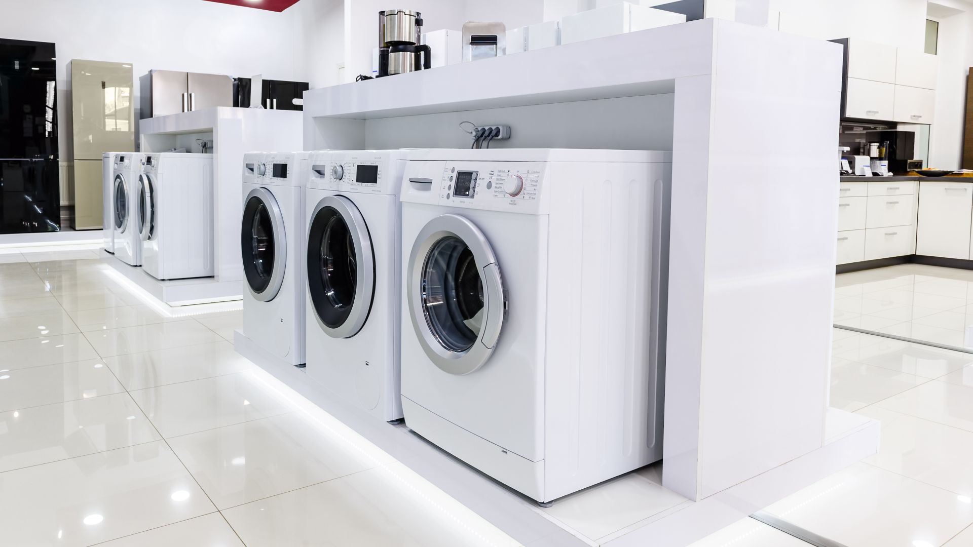 A row of washing machines are lined up in a store.