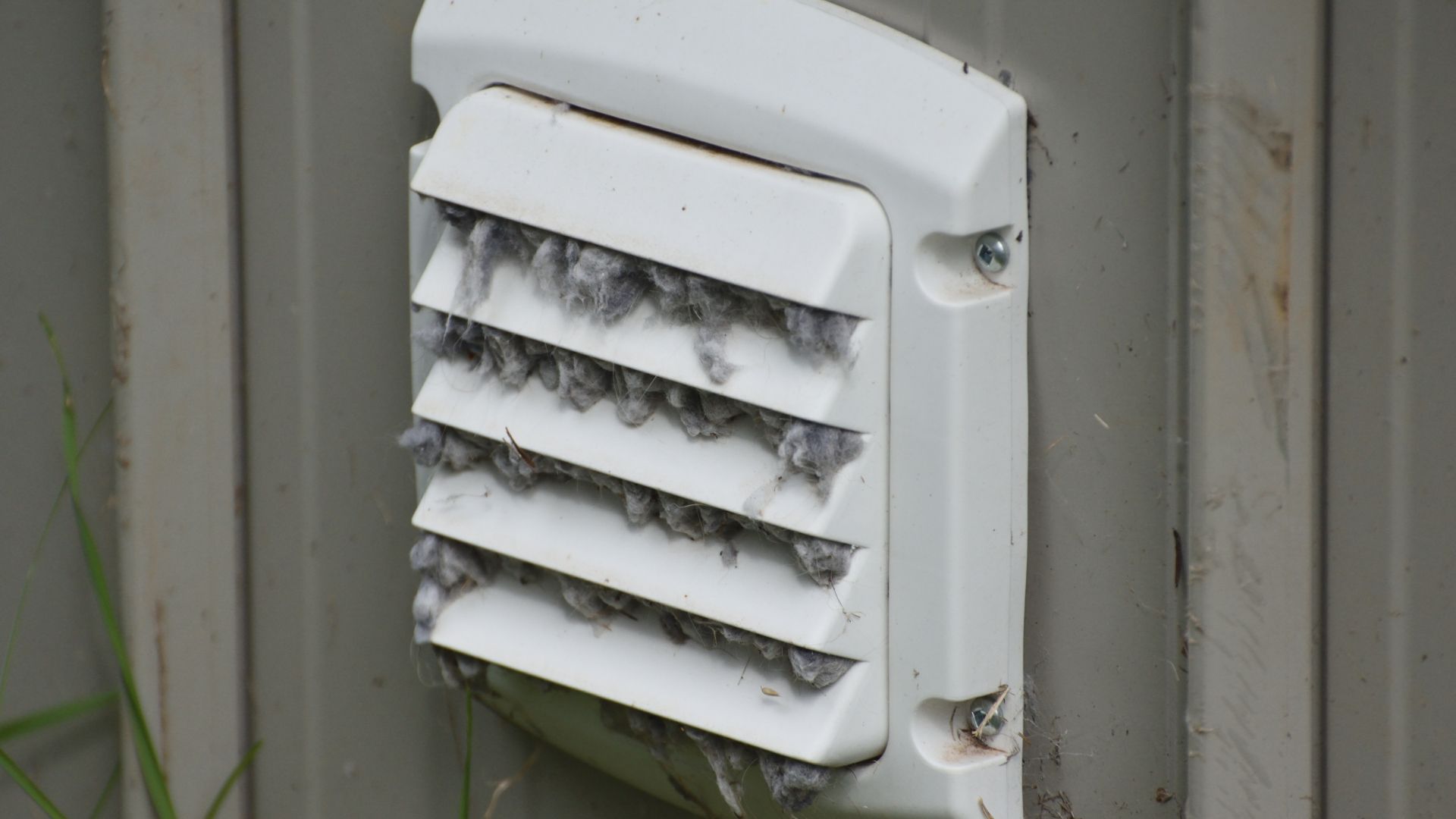 A white vent on a wall with a lot of dust on it.