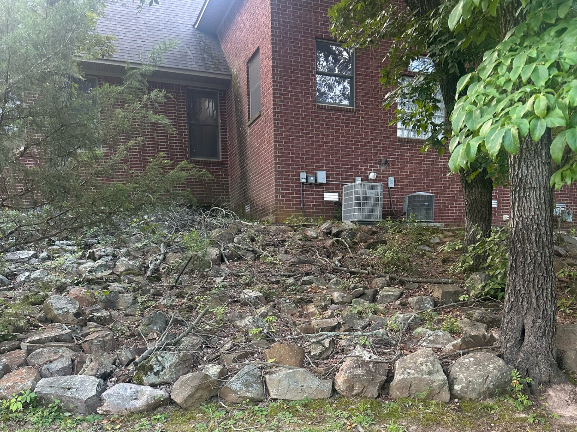 Brick house with a stone retaining wall and shrubbery.