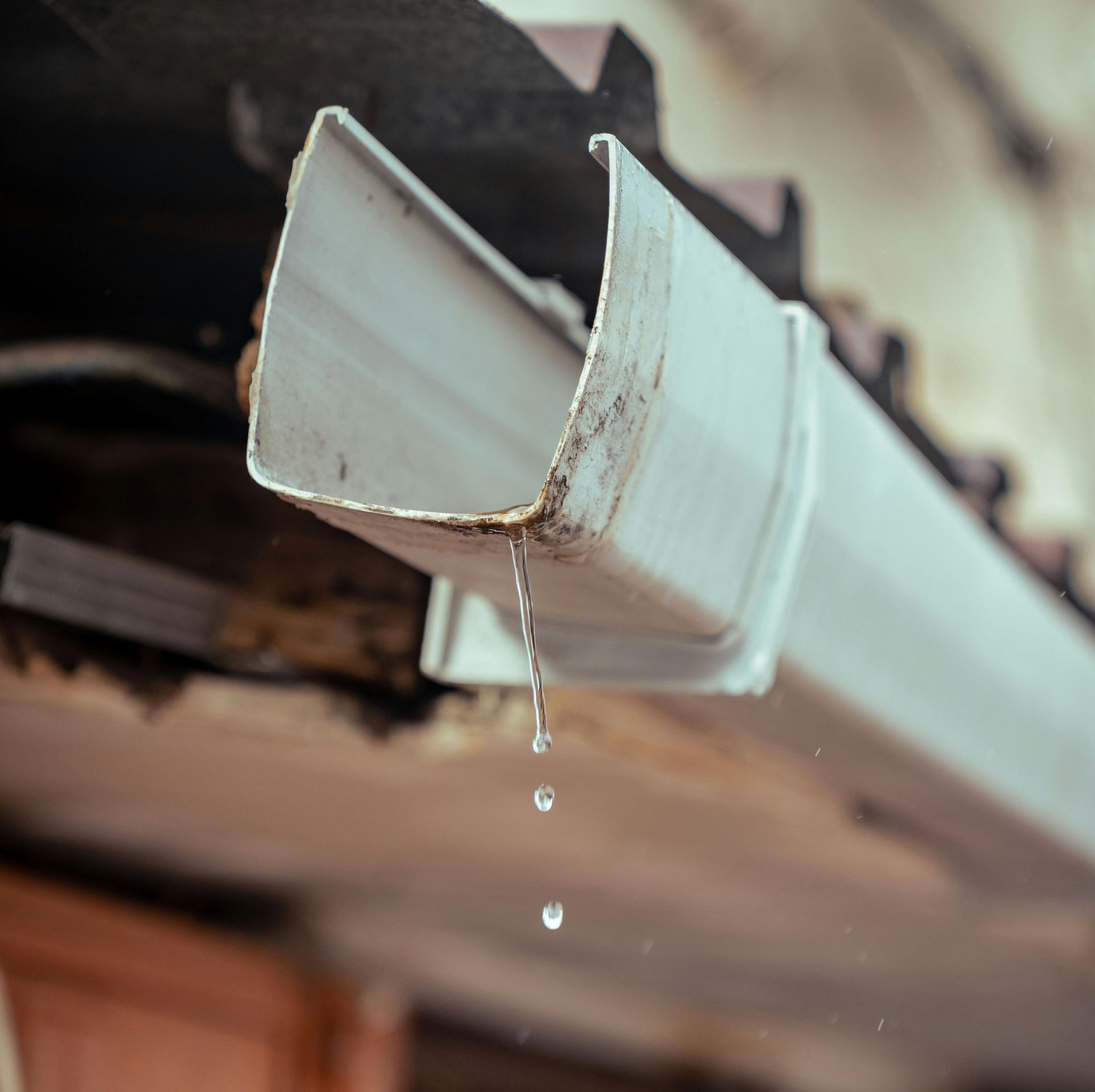 A white gutter with water dripping out of it