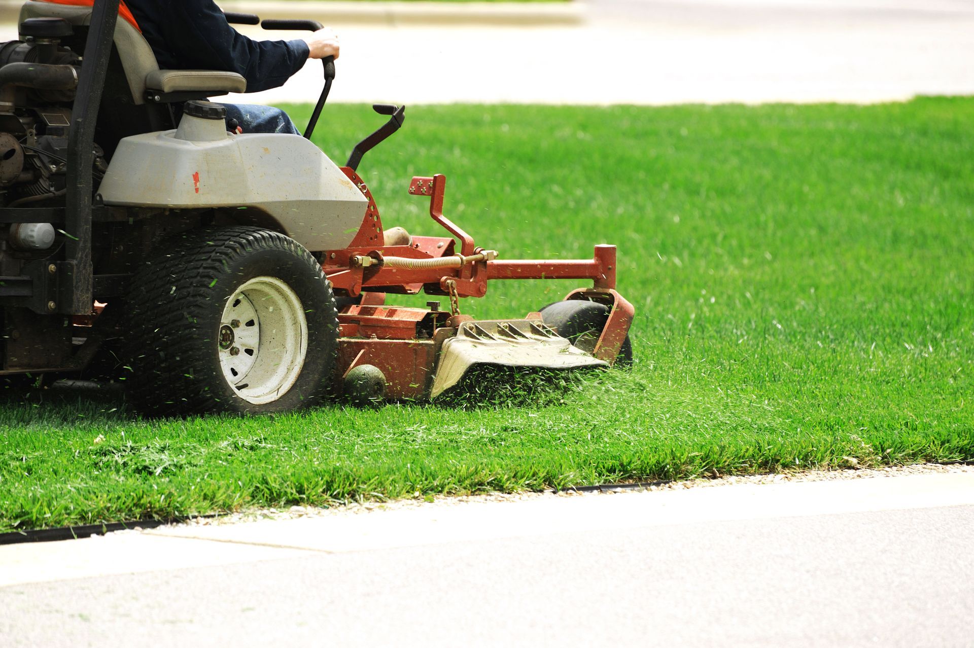 A man is riding a lawn mower to cut the grass.