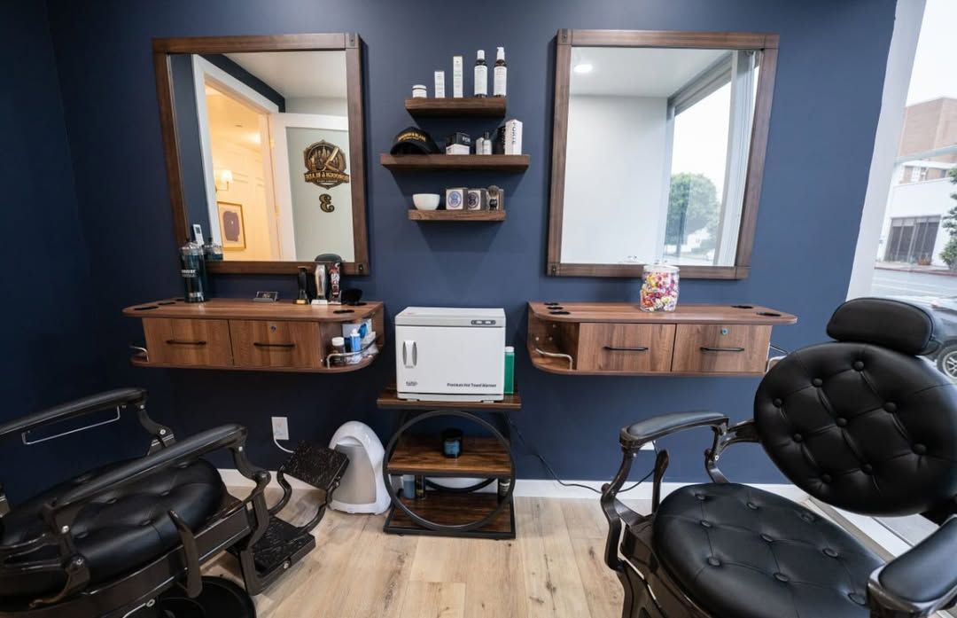 Modern barbershop with black chairs, wooden stations, and mirrors on a dark wall.