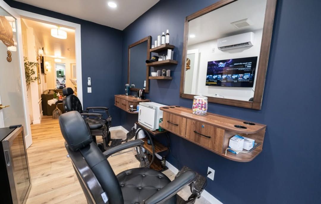 Blue-walled salon with styling chairs, mirror, shelves, and a wood countertop in a small room