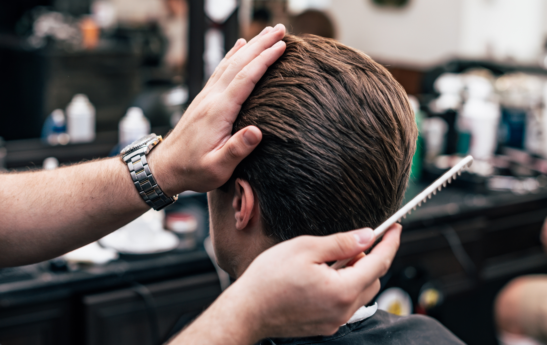Barber trimming a client’s hair with scissors in a salon