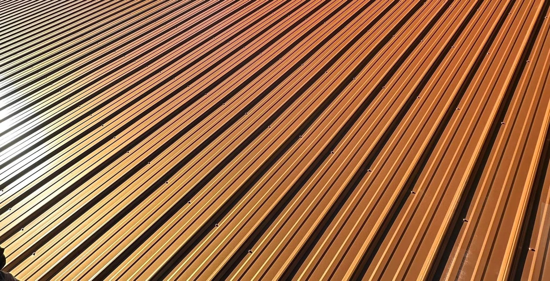 Corrugated metal roof, copper-toned with radiating lines and shadows.