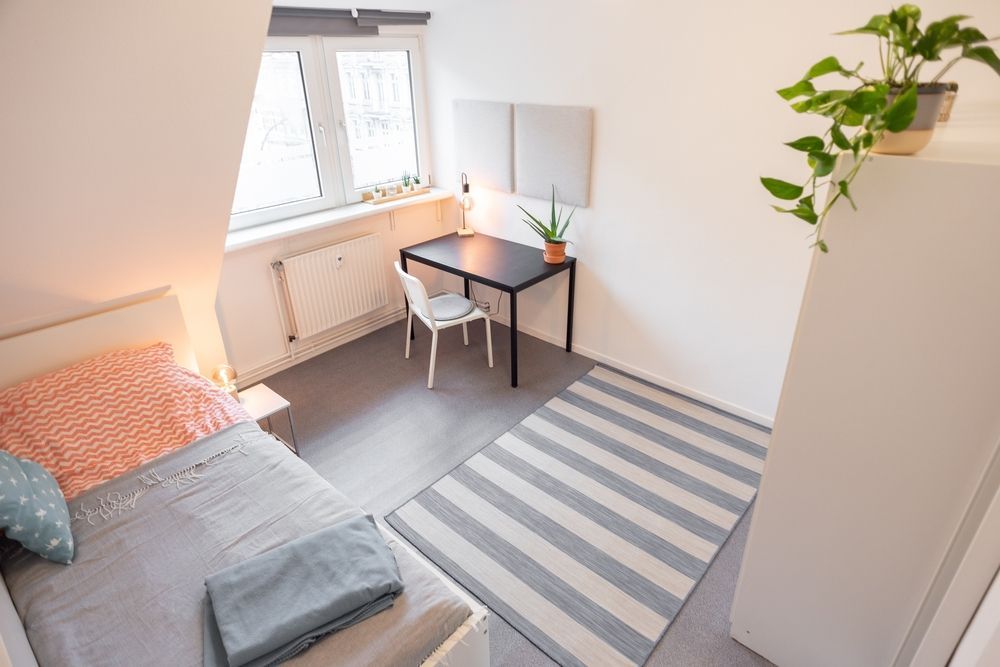 Bright minimalist modern dorm room bedroom in an apartment with a bed and a desk