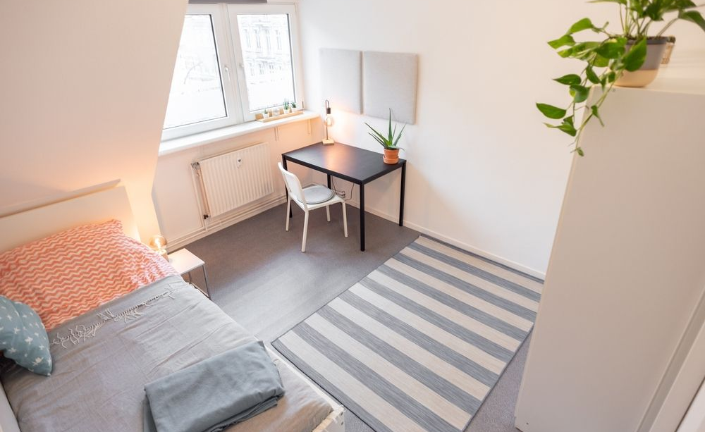 Bright minimalist modern dorm room bedroom in an apartment with a bed and a desk