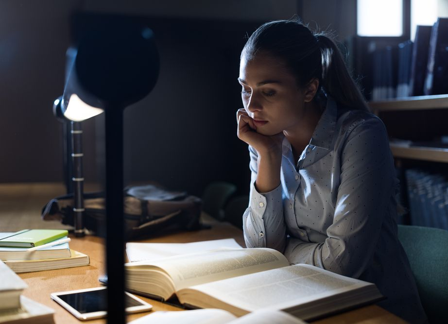 Efficient student girl studying late at night at the library, education and school concept