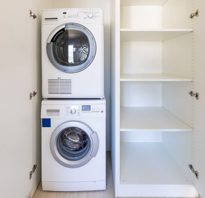 Front view of washing machine and dryer in a white cabinet with open doors.