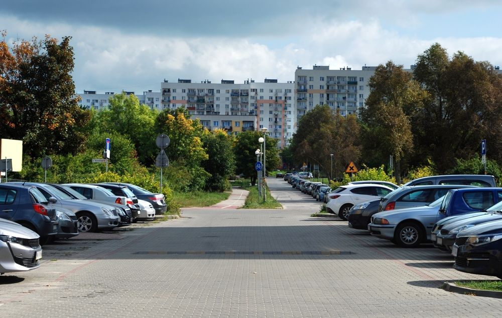 Parked cars in the parking lot and old apartment blocks in the distance.