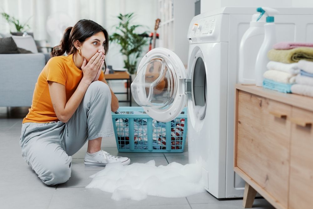 woman in distress while washing machine overloads with bubbles