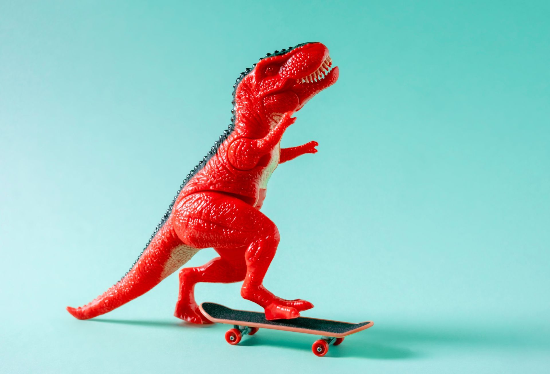 Red dinosaur on skateboard.