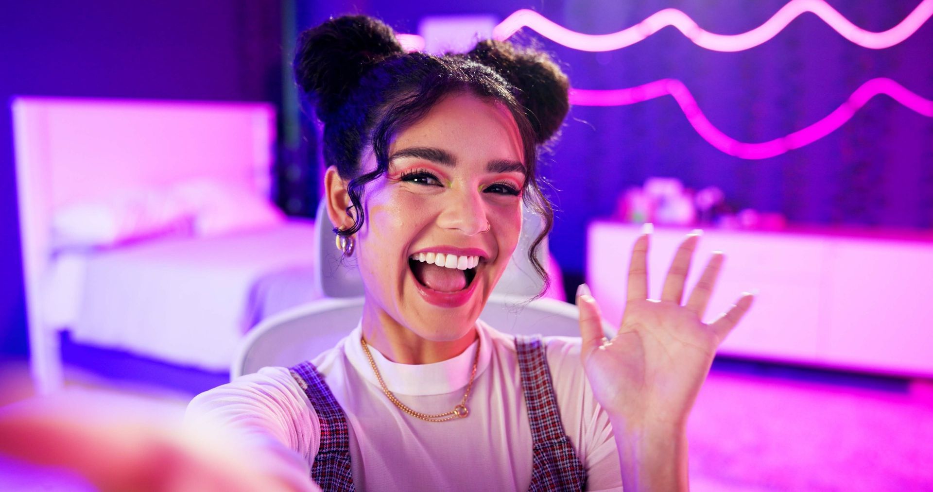 Girl with dark hair waving in her selfie image.
