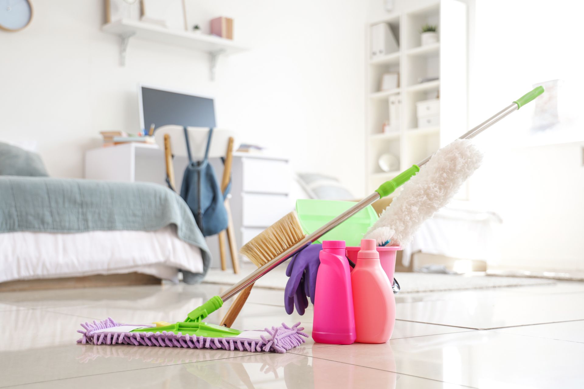 Mop and cleaning bottles in a dorm room.