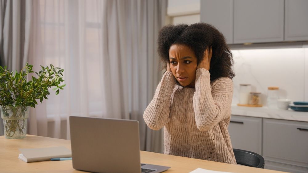 A lady covering her ears from a loud noise.