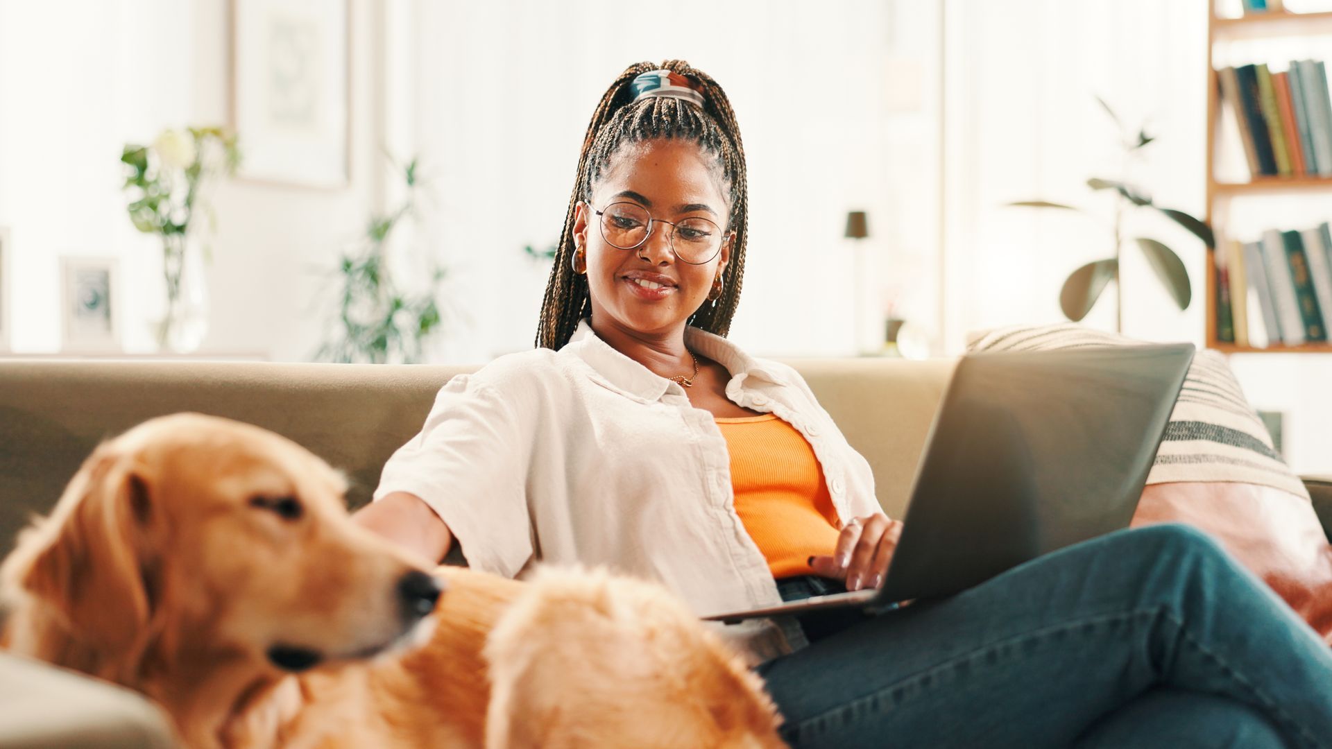 Girl sitting on the couch with her pet dog and laptop