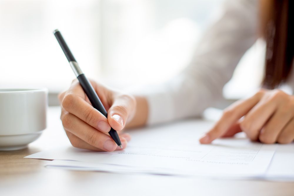 woman looking over and cosigning paperwork