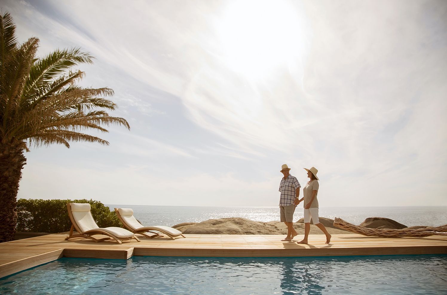 Couple walking poolside on a seaside deck with pool