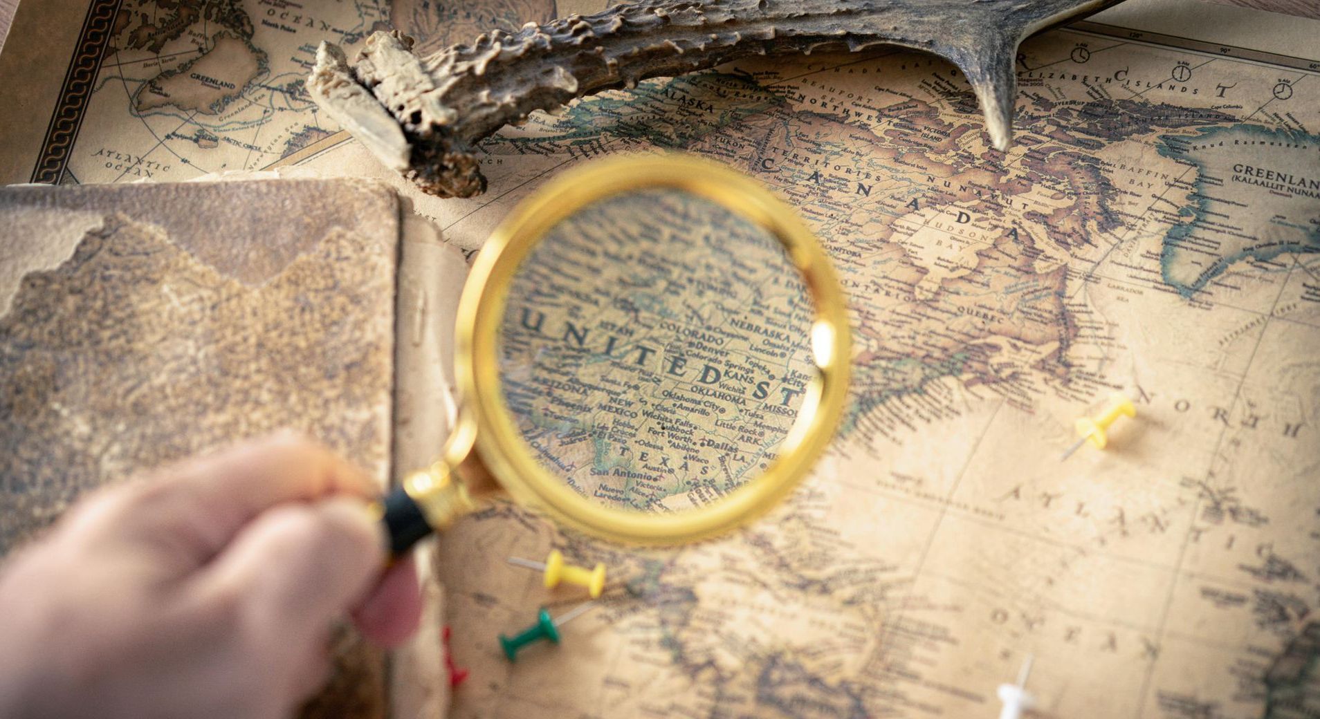 A person is holding a magnifying glass over a map.