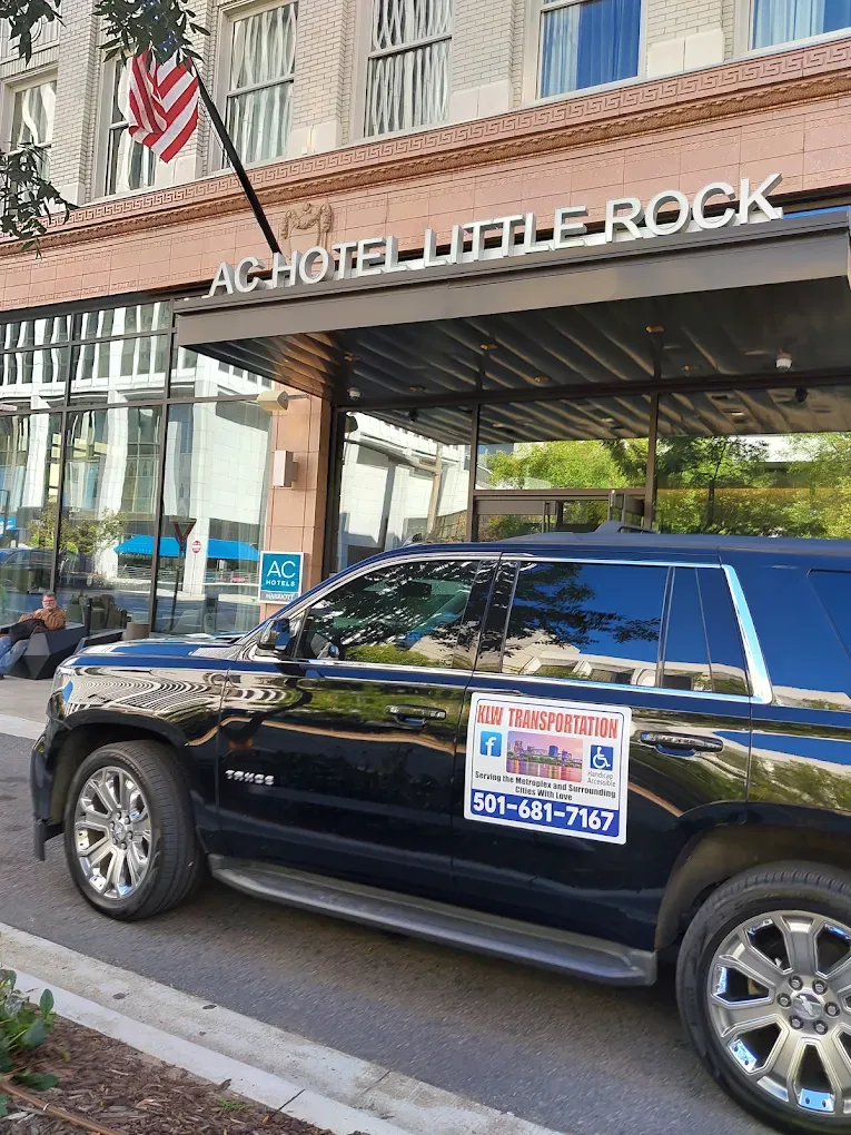 Black SUV parked at the entrance of the AC Hotel in Little Rock with American flag.