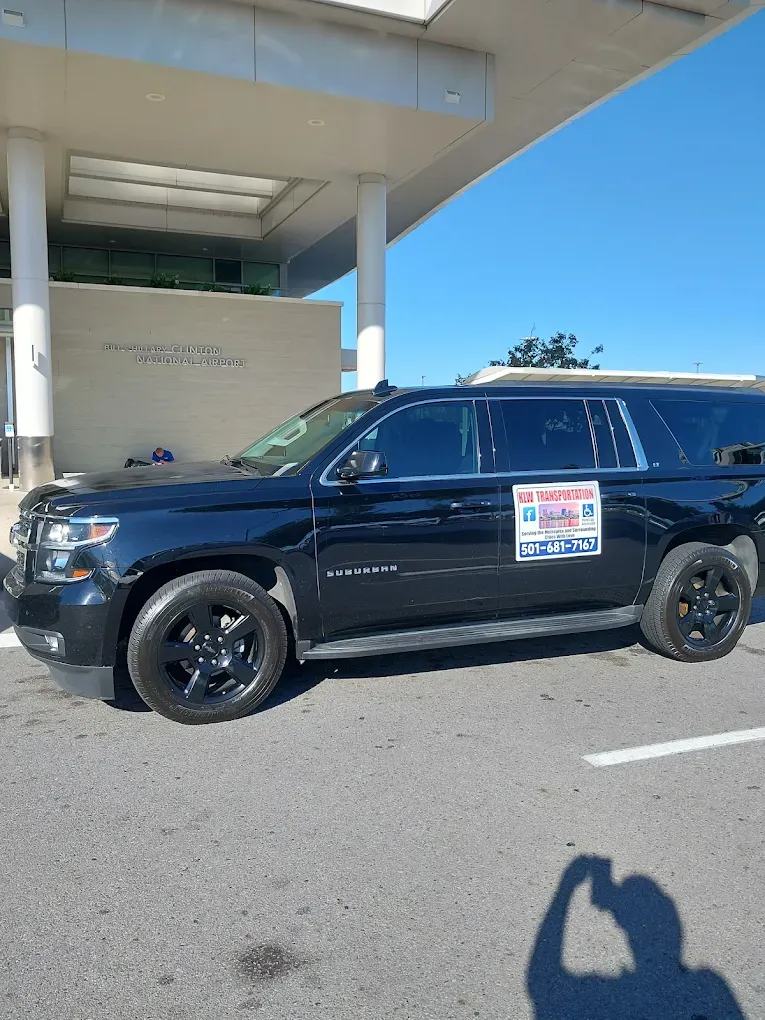 Black SUV parked near a building with columns, displaying a sign. Sunny day.