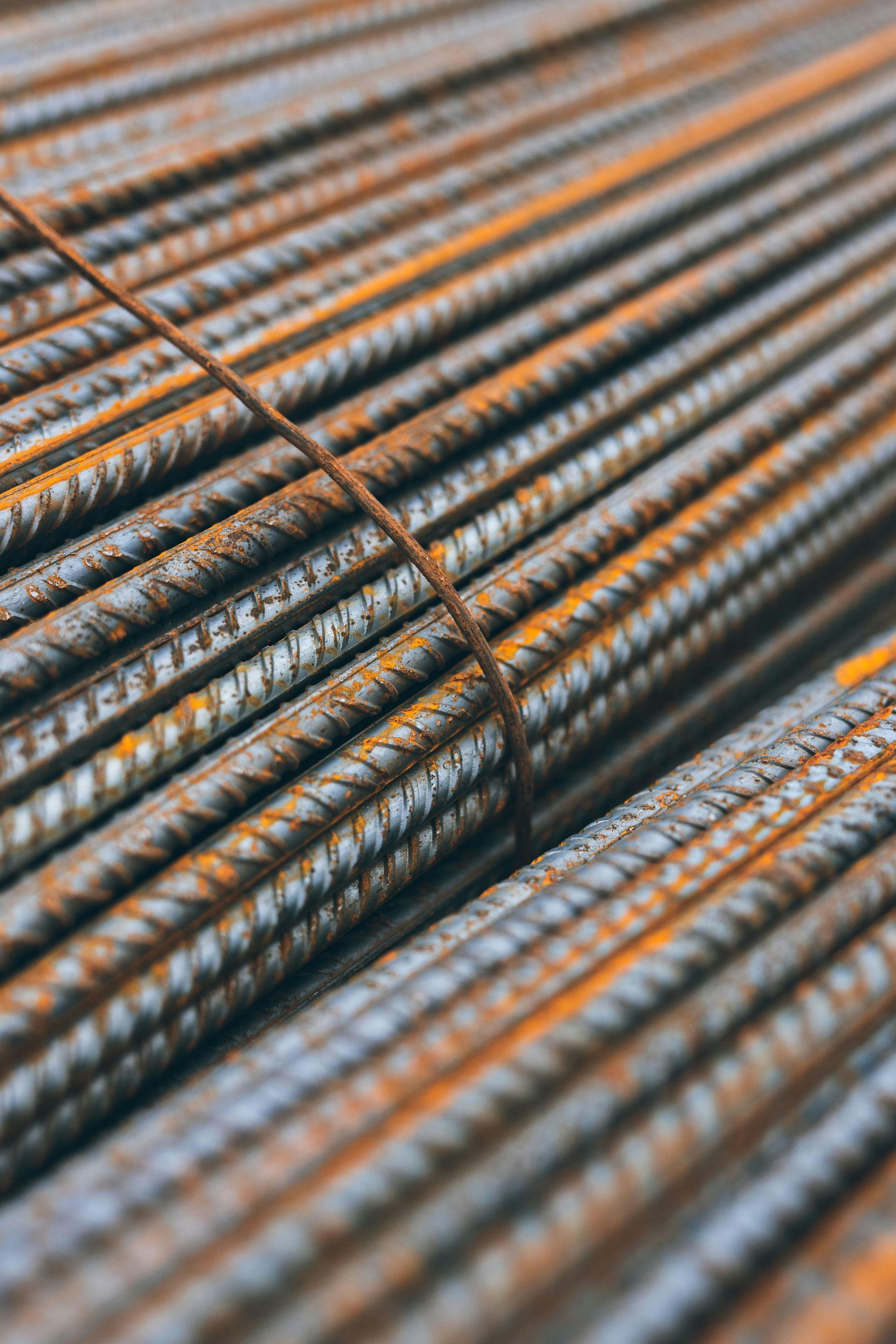 A close-up, angled view of a bundle of weathered, rusty steel rebar rods tied together with a thin metal wire.
