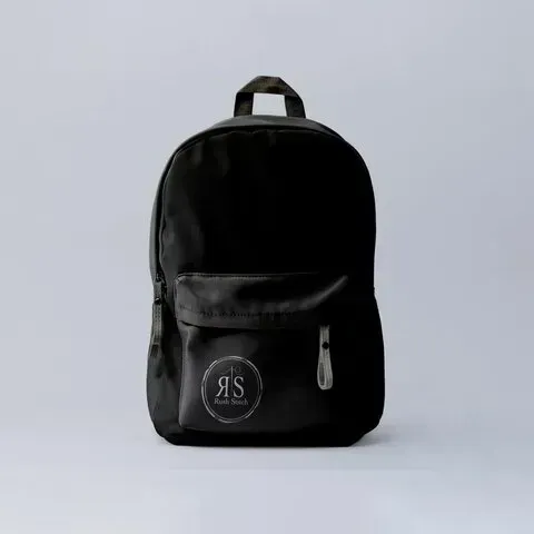 Una mochila negra reposa sobre una superficie blanca.