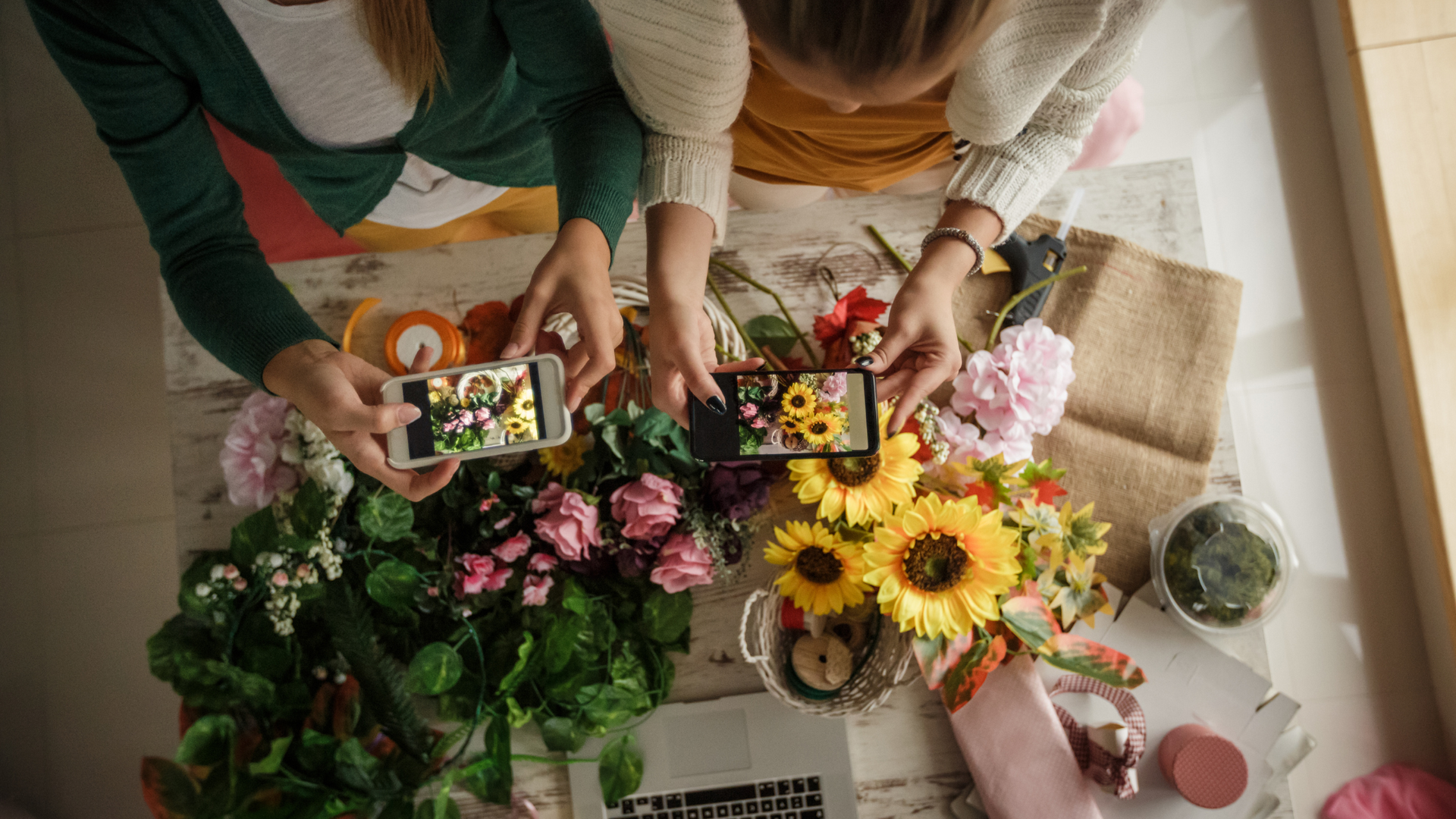 Two florists take photos of their flowers with their cameras for social media.