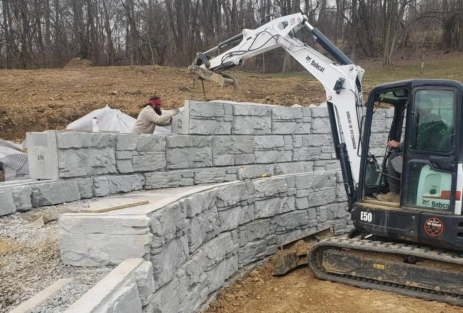 Mini excavator installing a large block retaining wall in Montgomery County, TX.