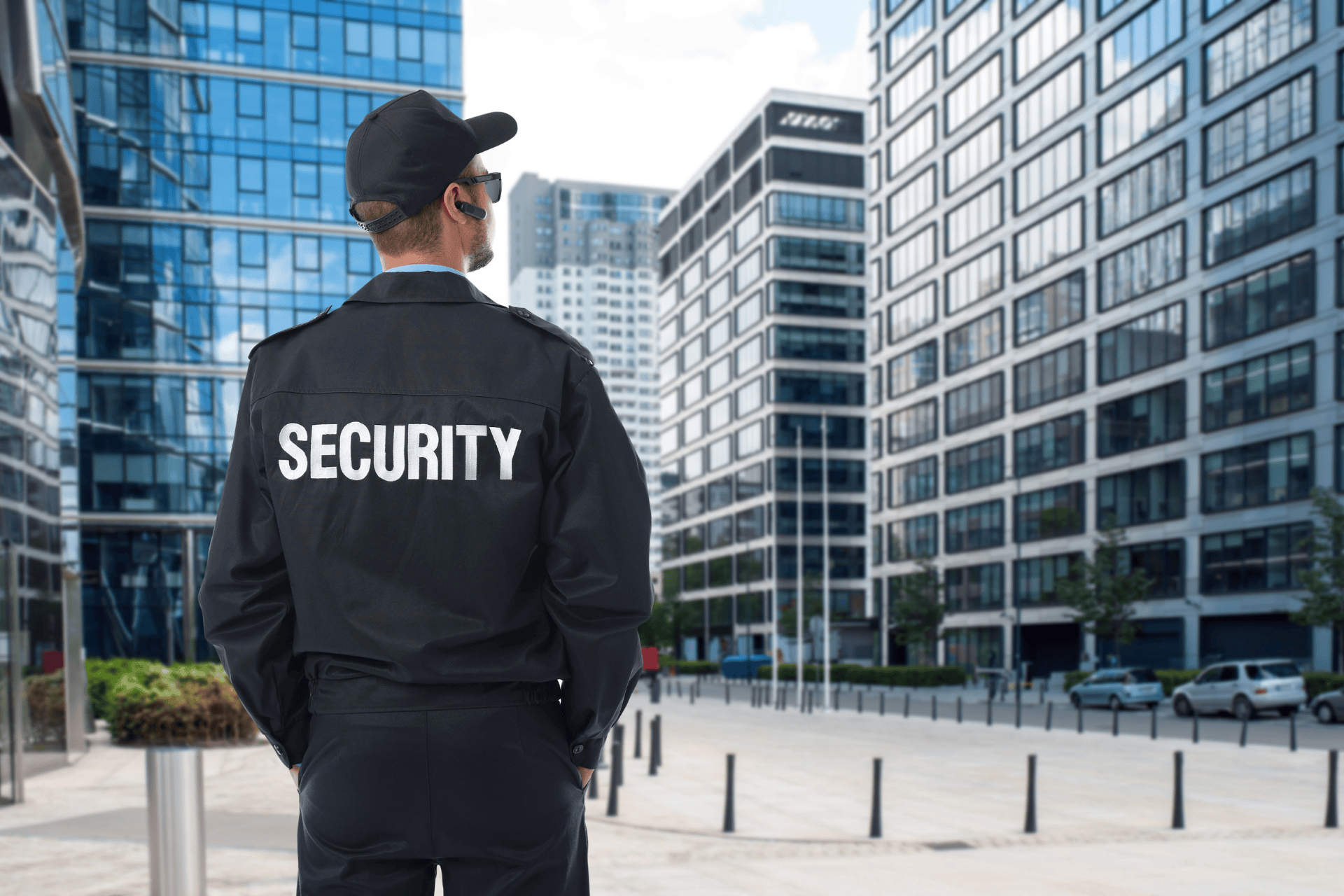 Security guard standing on patrol outside modern office buildings in a downtown business district, monitoring the area for safety and access control.