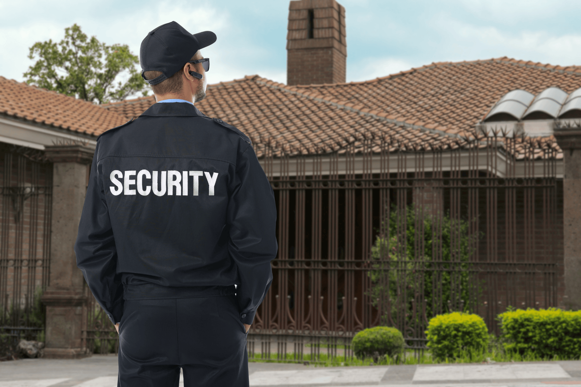 Security guard standing watch outside a gated residential property, monitoring the perimeter and ensuring safety at a private home.
