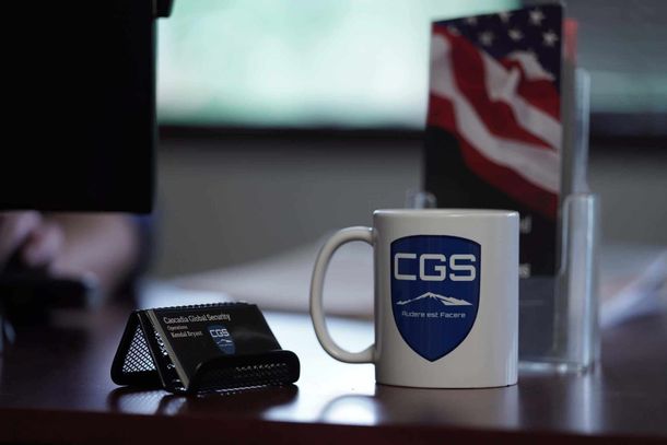 A cgs mug sits on a desk next to a business card holder