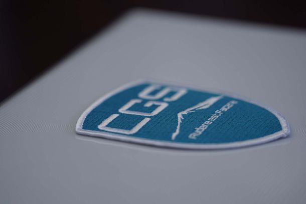 A close up of a blue and white badge on a white surface.