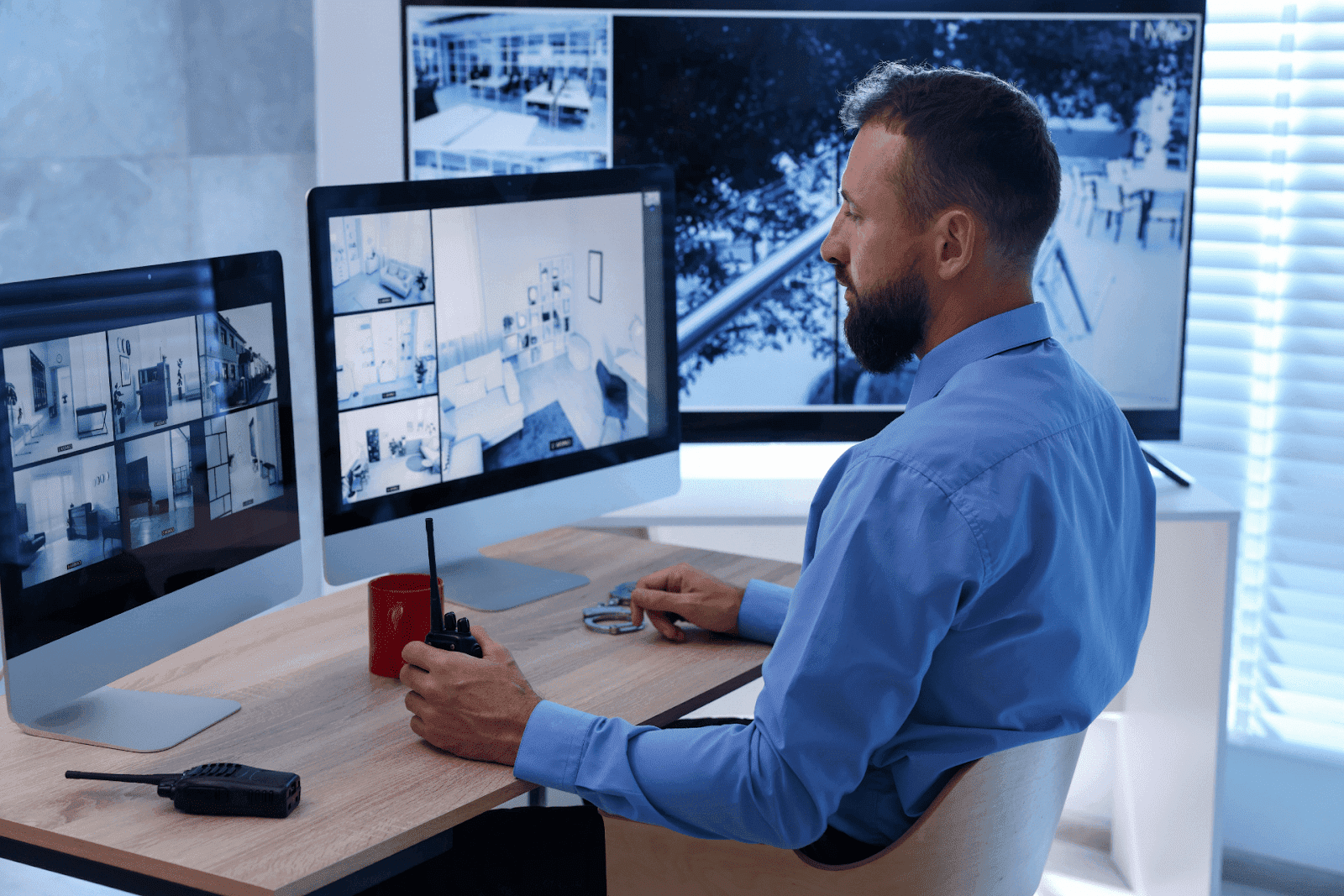 Man monitoring multiple security camera feeds at a desk.