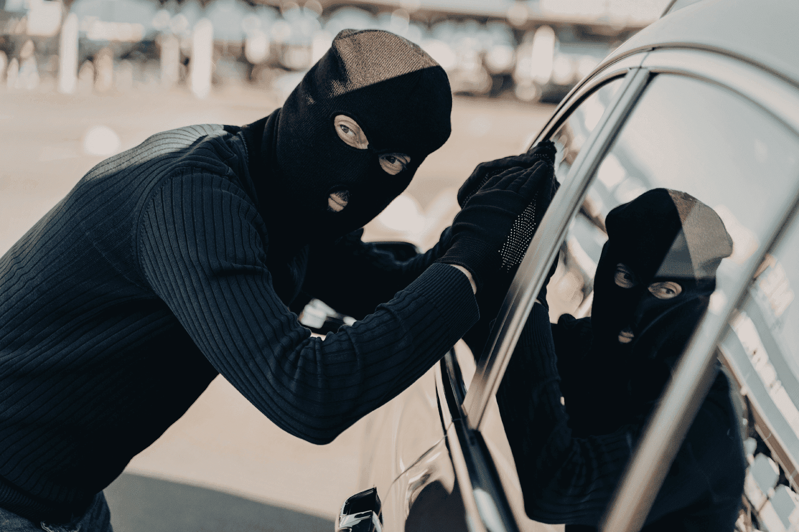 Masked person attempting to break into a parked car.