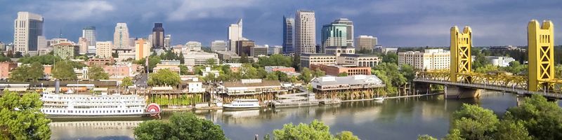 Skyscrapers with mirrored glass reflecting the blue sky and clouds, seen from a low angle.